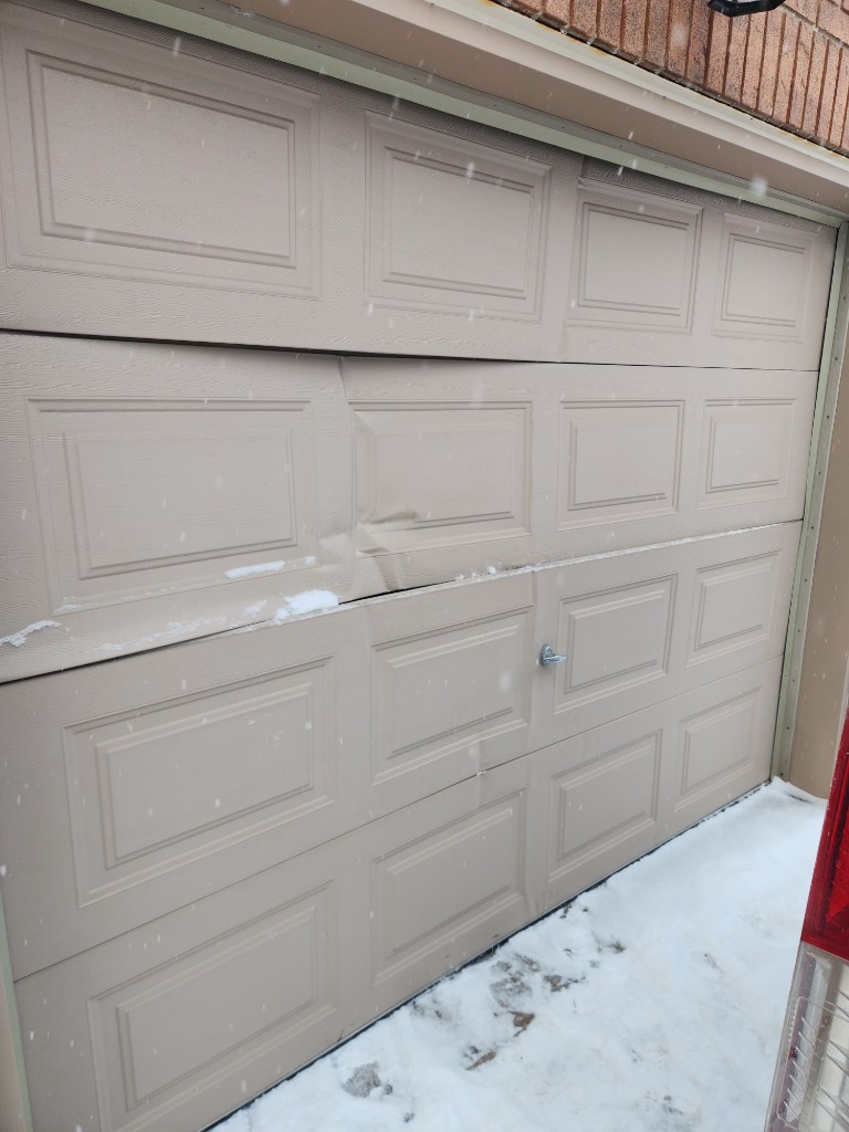 Bent garage door panel after winter impact in Stittsville