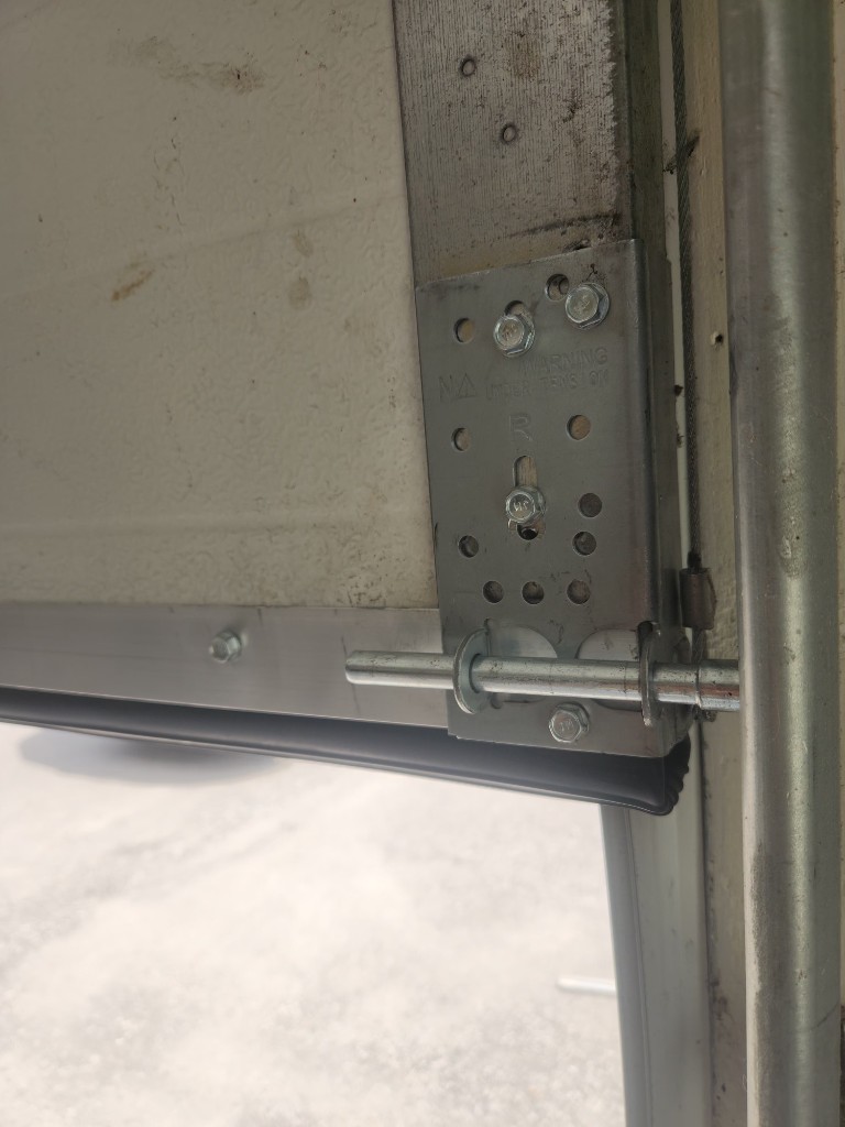 New bottom bracket, lift cable, roller, and aluminum bottom seal installed on a Stittsville garage door