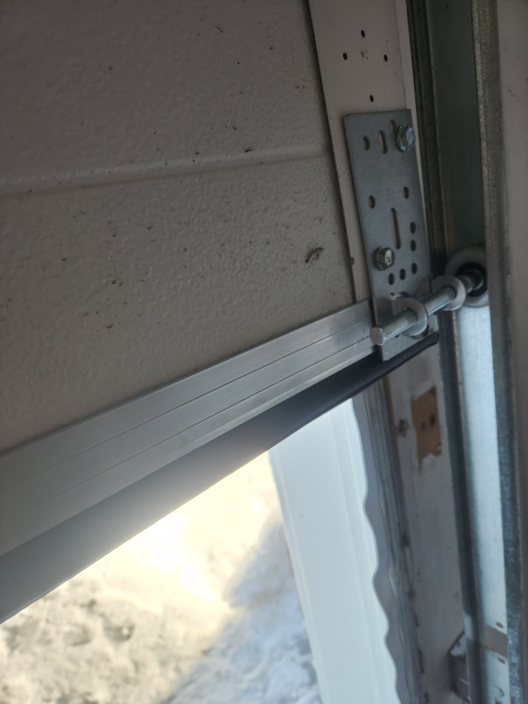 New aluminum bottom seal retainer, rubber bottom seal, roller, and bottom bracket installed on a Stittsville garage door