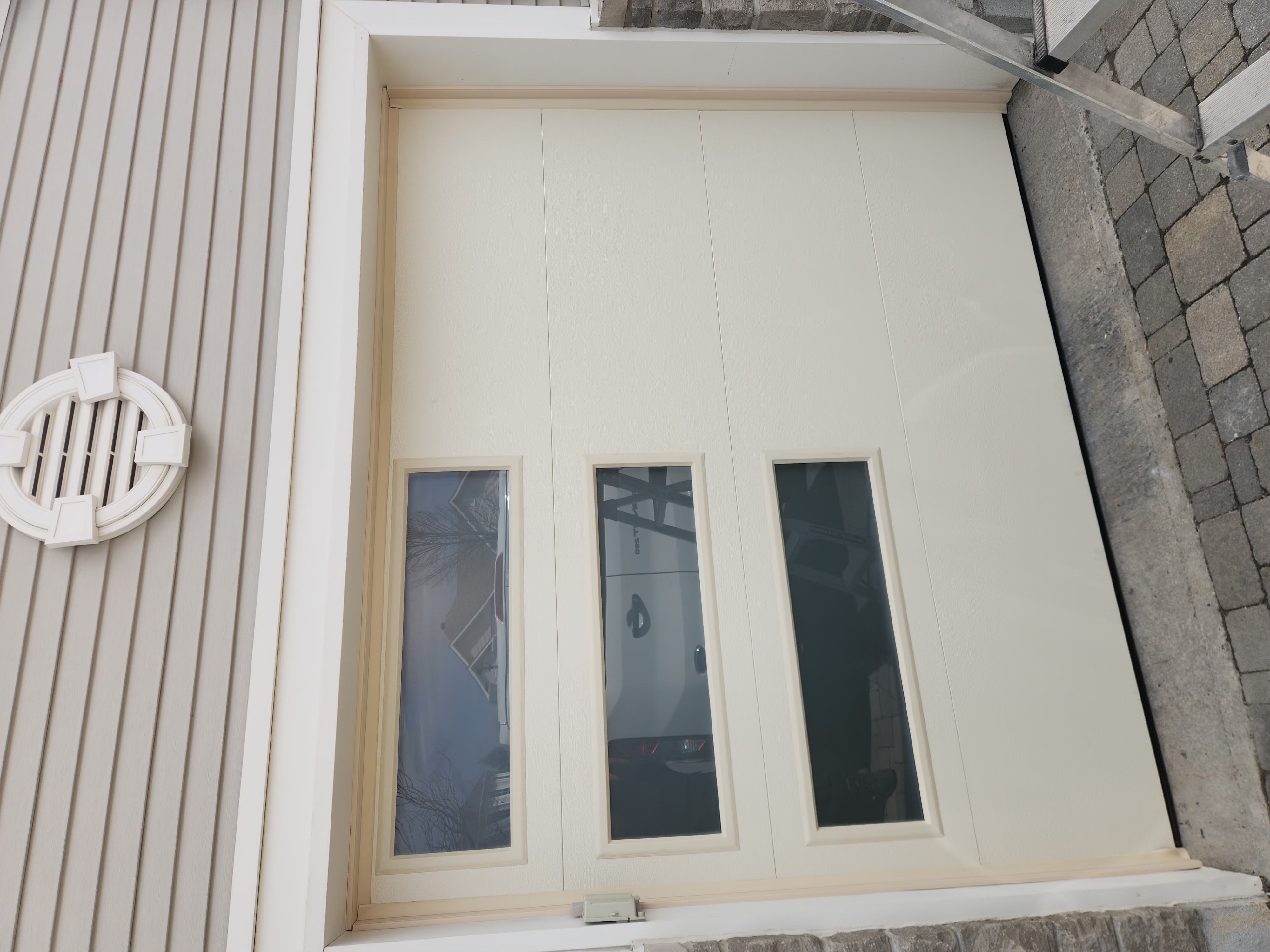 New cream flush-panel garage door with three windows installed in Stittsville
