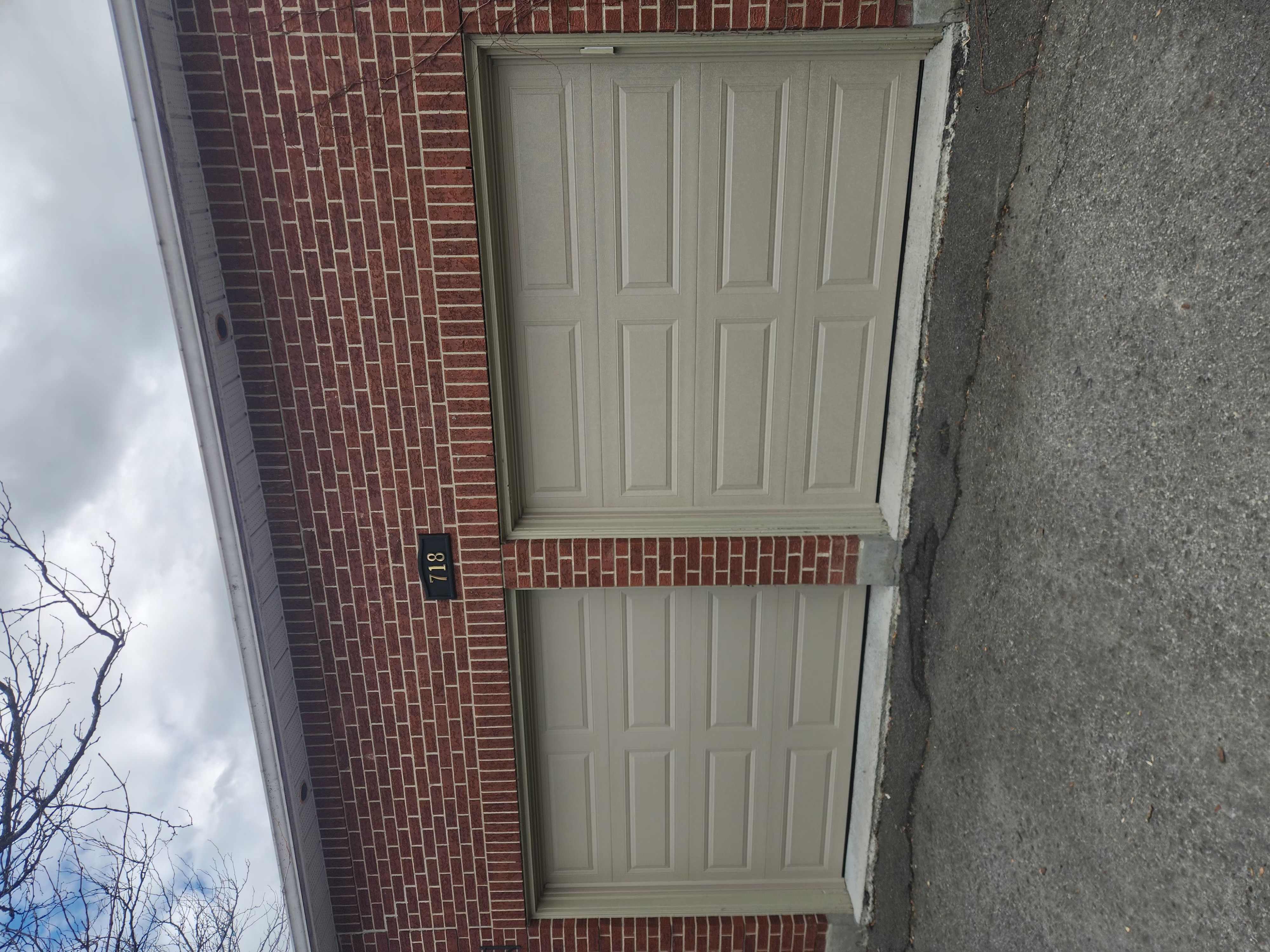 Two new beige raised-panel garage doors installed on brick home in Stittsville