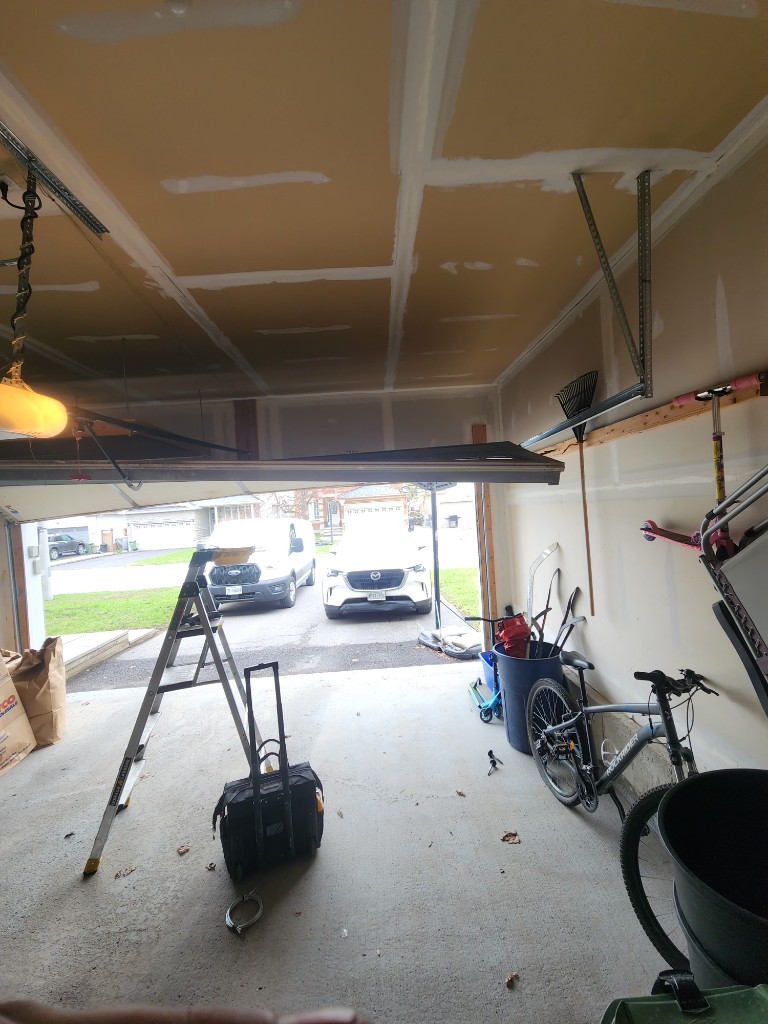 Interior view of a Stittsville garage with a sectional door off the vertical track, rollers out of the channel