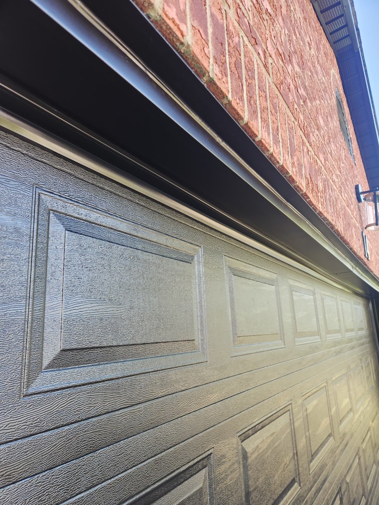 Detail of new top weather stripping installed above a wood-look garage door in Stittsville