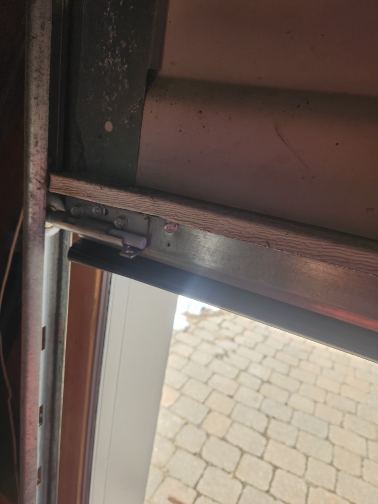 Worn top weather stripping along the header of a Stittsville garage door before replacement