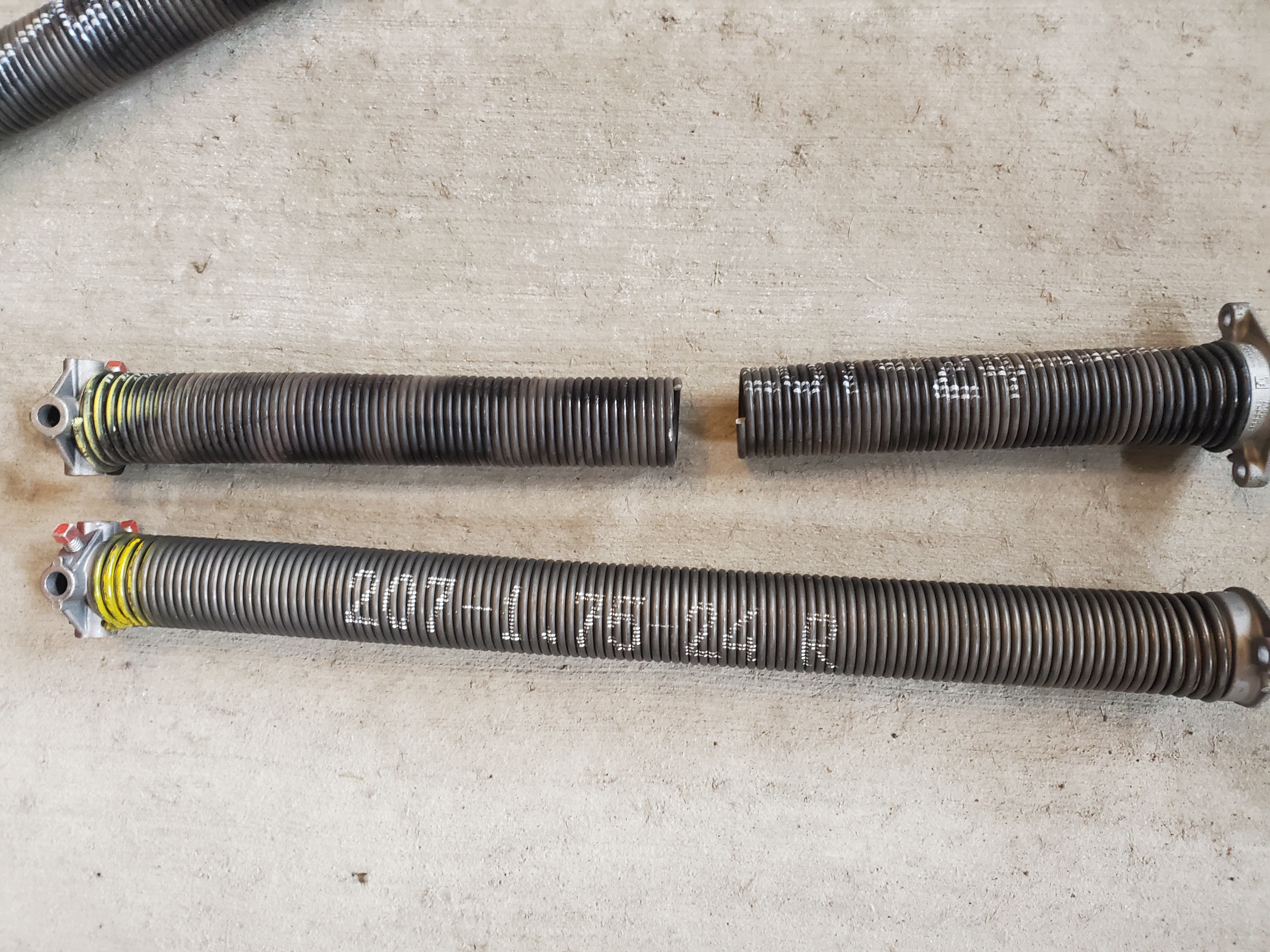 Removed broken torsion springs laid out on concrete during a Stittsville spring replacement
